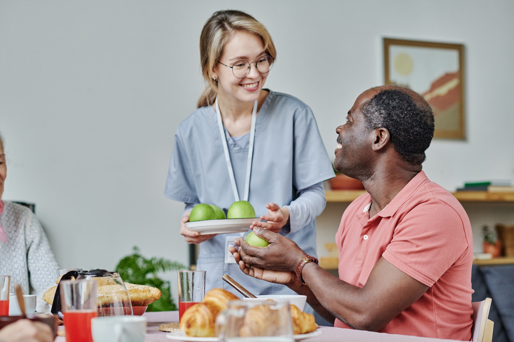 Caregiver giving apples to senior man