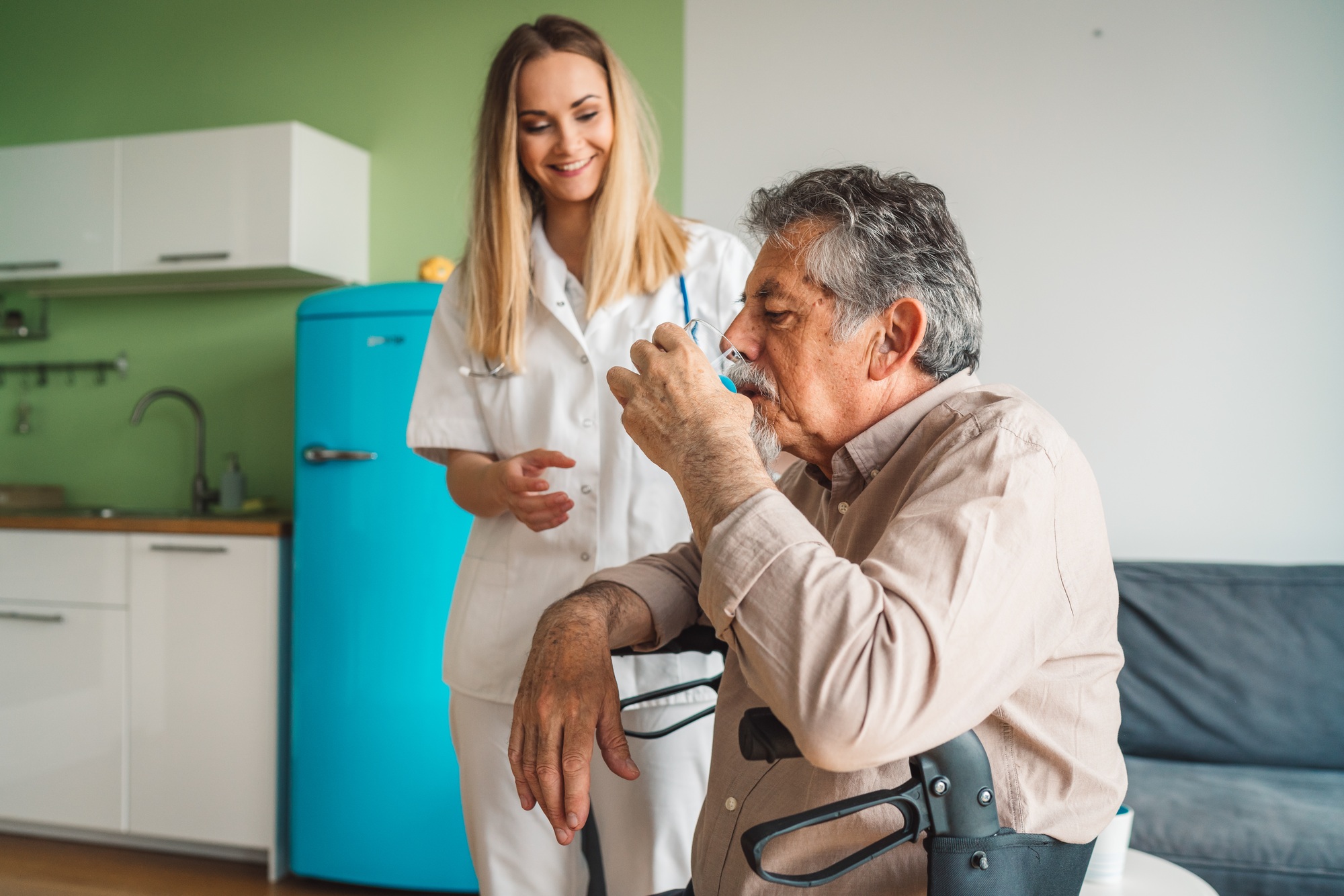 Young caregiver helping senior man at the nursing home